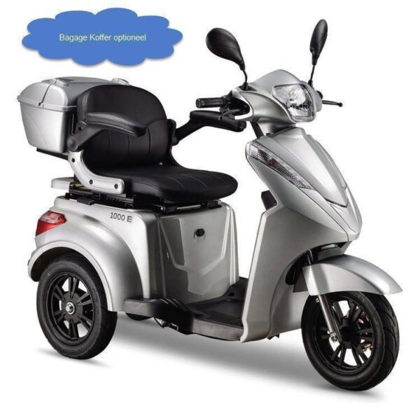 Zilveren IVA e1000 driewielige elektrische scooter met gepolsterde zitting en opbergruimte achterin. Boven de scooter hangt een blauwe wolkvormige notitie met de tekst Bagage Koffer optioneel voor optionele bagageopslag.